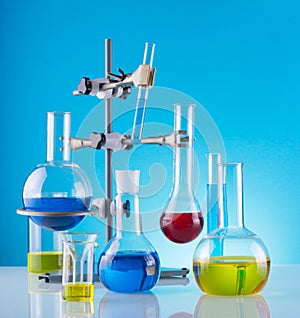 Biological laboratory. A tripod with variety of chemical glass and colored liquids on a blue background