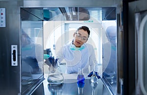 Biologist putting chemical bottles in incubator