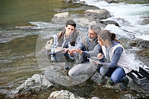 Biologist with students testing river water