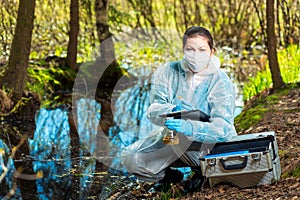 biologist takes water from a forest river to study the composition