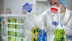 Biologist taking yellow organic liquid sample for analysis, cosmetology extract