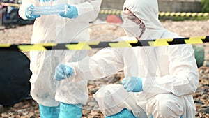 Biologist wear protective suit and mask collects sample of waste water from