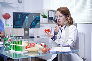 Biologist in white coat in a research lab injecting liquid in a tomato