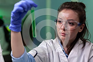 Biologist woman doctor holding medical test tube with green dna solution