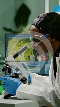 Biologist woman looking at test sample under microscope