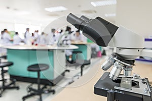 Biology or chemistry science class study with microscope and blur background of school student group learning in blurry lab