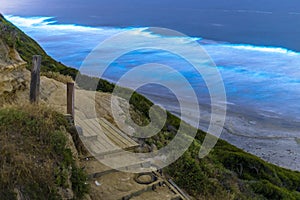 Long exposure of Beautiful Blue Bioluminescence at Black`s Beach in San Diego. Trail and wooden stairs in the foreground. photo