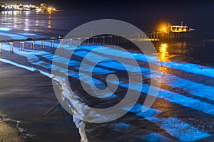 Bioluminescent tide makes the waves glow blue around the Scripps Pier in La Jolla, California photo