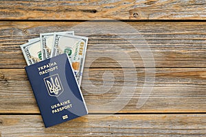 Biometric Ukrainian passport and money on a wooden background, copy space.