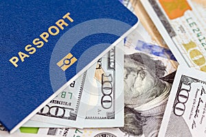 Biometrical international passport over money background. Blue travel documents lying on US one hundred dollar banknotes. Tourism