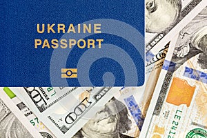 Biometrical Ukrainian passport over money background. Ukraine citizen travel documents lying on US one hundred dollar banknotes. V
