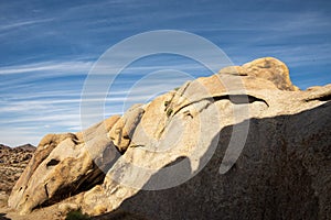 Biomorphic rock formations in California desert streaky clouds in blue sky
