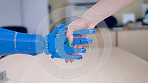 A bionic hand being shaken by a human female one.