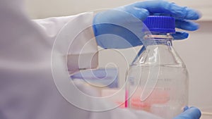 Biotechnologist prepares a bottle for chemical experiment