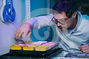 Biotechnology concept with scientist in lab. Scientist watering a plant with a special solution.