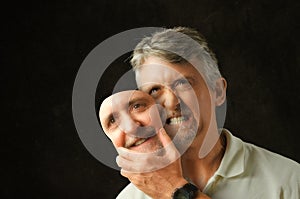 Bipolar disorder angry emotional man with fake smile mask photo
