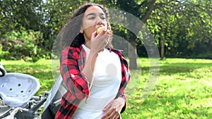 Biracial African American mixed race teenage girl young woman eating an apple by a tractor in an orchard