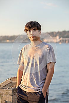 Biracial Asian Caucasian young man outdoors by lake near sunset