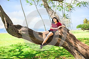 Teen girl in tree at Kawaikui Beach park, Oahu, Hawaii