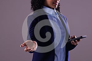 Biracial businesswoman using smartphone with copy space on grey background