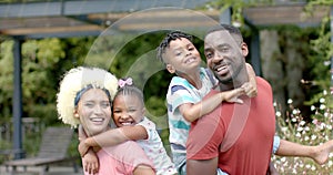 Biracial family enjoys sunny day together, showing affection outdoors.