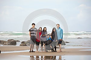 Biracial family of six together on the beach by ocean