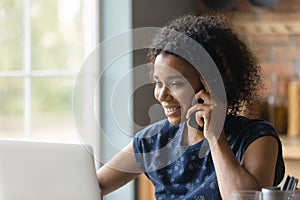 Biracial female hold cell at ear look at pc screen