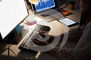 Biracial female programmer sitting at desk, using computer with coding on screen