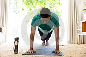 Biracial man exercising and doing push ups on mat at home