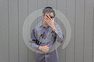 Biracial man looking between fingers of hand over face, adjusting eyeglasses, natural hair in dreadlock hairdo