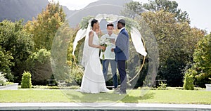 Biracial man officiating marriage of happy african american couple in sunny garden, in slow motion