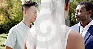 Biracial man officiating marriage of happy african american couple in sunny garden, in slow motion