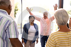 Biracial seniors male and female welcoming cheerful friends in nursing home, copy space
