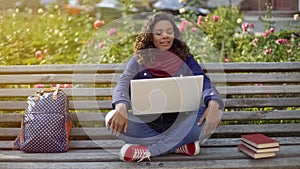 Biracial student in good mood sitting on bench, dreaming about bright future