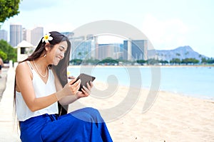 Biracial teen girl on beach using tablet computer, Waikiki, Honolulu