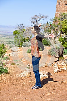 Biracial teen girl raising arms in praise at the Grand Canyon