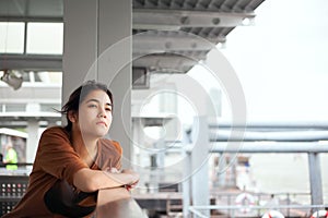 Biracial teen girl sitting by dock, looking up thinking