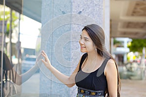 Biracial teen girl window shopping, looking into store front glass