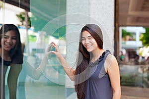 Biracial teen girl window shopping in urban setting downtown