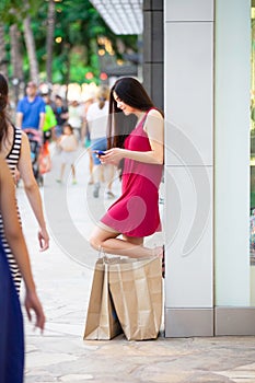 Biracial teen in red dress outside stores with shopping bags