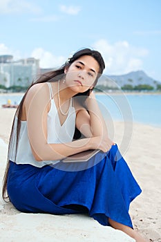 Biracial teen sitting on Hawaiian beach, thinking. Waikiki, Honolulu