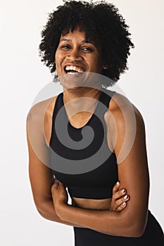 Biracial woman with curly hair laughing in studio, wearing black sportswear