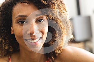 A biracial woman with curly hair smiles warmly at the camera