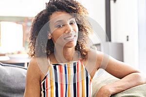 Biracial woman with curly hair smiles, wearing a striped top