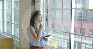 Biracial woman ponders a business problem in a bright office