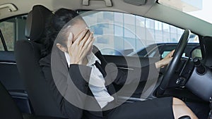 Biracial woman in suit sitting in auto, hitting steering wheel, annoyance