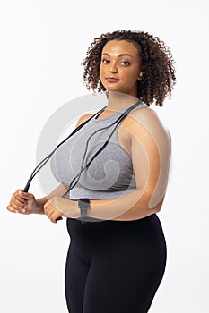 A biracial young female plus size model holding a jump rope on a white background