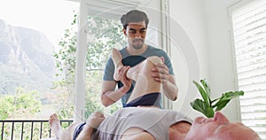 Biracial young male therapist treating leg of retired senior man at health club