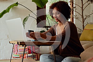 Biracial young woman doing banking on laptop in living room at home