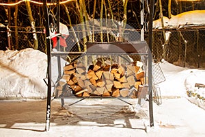 Birch firewood prepared for bbq. Are lying under the grill in snow. Winter night